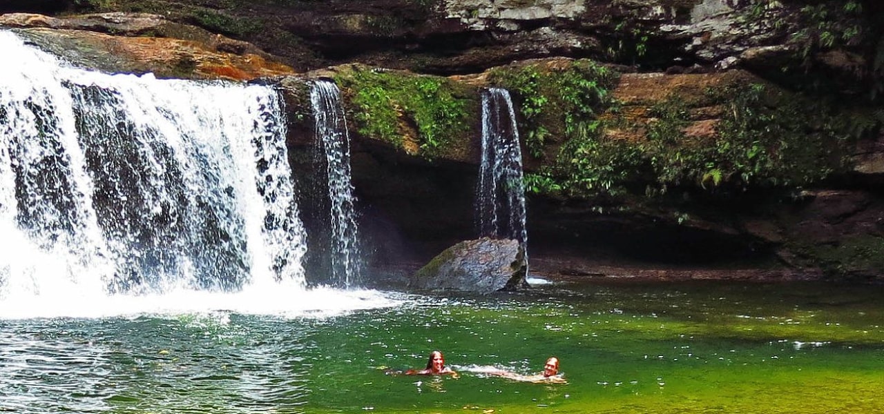 Tourists swimming in a natural pool and waterfall in Putumayo