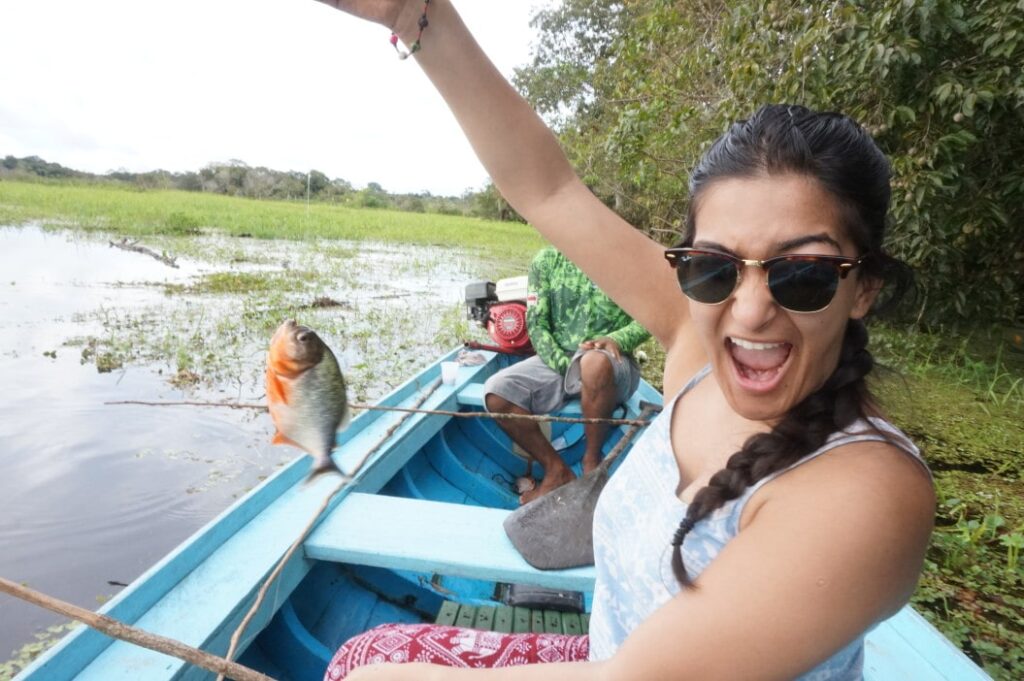 Tourist celebrating having caught a piranha in the Amazon river Colombia