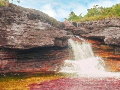 Waterfall in Caño Cristales, red and yellow colors of the plants. Rainbow river Colombia